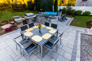 Mid-sized trendy backyard concrete paver patio photo in Manchester with a fire pit and no cover