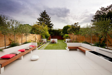 Photo of a medium sized contemporary back patio in London with a water feature, tiled flooring and no cover.