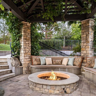 Foto di un patio o portico classico di medie dimensioni e dietro casa con un gazebo o capanno, un focolare e pavimentazioni in pietra naturale