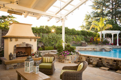 Ispirazione per un grande patio o portico chic dietro casa con un caminetto, pavimentazioni in pietra naturale e una pergola