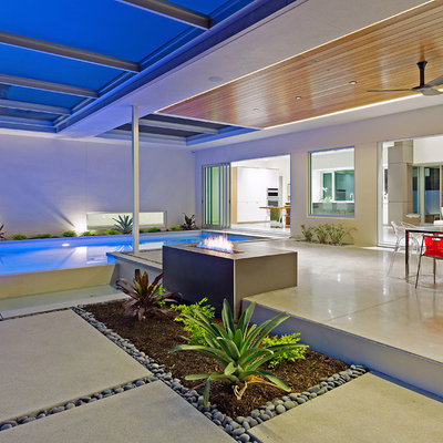 Inspiration for a large contemporary backyard concrete patio remodel in Tampa with a fire pit and a roof extension