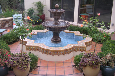 Diseño de patio mediterráneo de tamaño medio sin cubierta en patio con fuente y suelo de baldosas