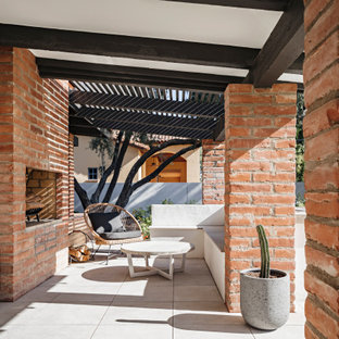 Foto di un patio o portico stile americano con un caminetto e una pergola