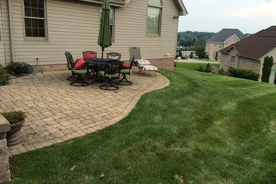 Example of a mid-sized classic backyard brick patio design in Other with no cover