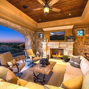Esempio di un ampio patio o portico shabby-chic style dietro casa con un focolare, pavimentazioni in cemento e un tetto a sbalzo