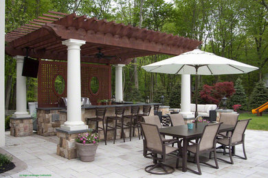 Inspiration for a mid-sized contemporary backyard stone patio kitchen remodel in New York with a pergola