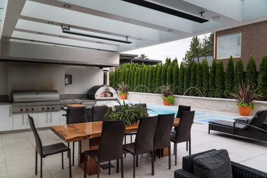 Idée de décoration pour une petite terrasse arrière design avec une cuisine d'été, du béton estampé et une extension de toiture.