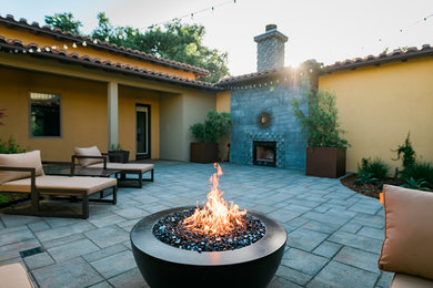 Example of a mid-sized tuscan courtyard concrete paver patio design in San Luis Obispo with a fire pit