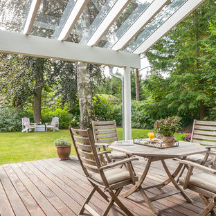 Esempio di un patio o portico nordico dietro casa con pedane e un tetto a sbalzo