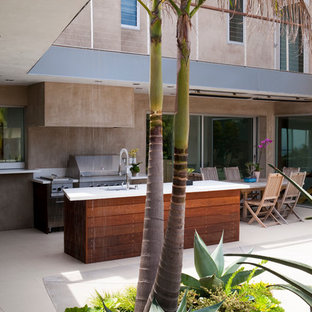 Immagine di un grande patio o portico tropicale dietro casa con lastre di cemento e un tetto a sbalzo
