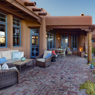 Example of a southwest brick patio design in Albuquerque with a roof extension