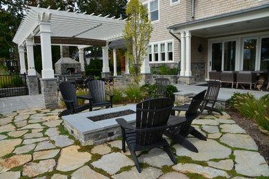Example of a mid-sized beach style backyard stone patio design in New York with no cover