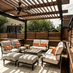 Foto di un patio o portico minimal di medie dimensioni e dietro casa con un focolare, piastrelle e una pergola