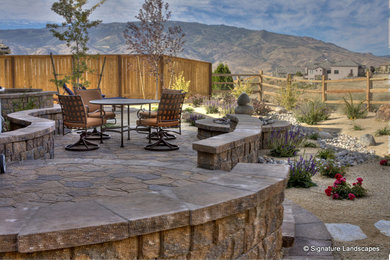Imagen de patio de estilo americano de tamaño medio sin cubierta en patio trasero con fuente y adoquines de piedra natural