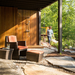 Ispirazione per un patio o portico american style dietro casa e di medie dimensioni con pavimentazioni in pietra naturale e un tetto a sbalzo