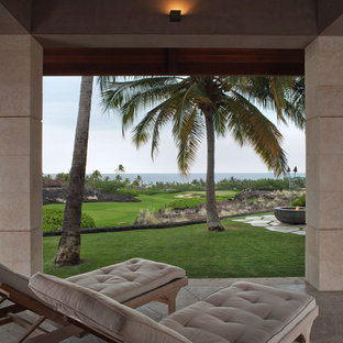 Foto di un ampio patio o portico etnico dietro casa con un focolare, piastrelle e un tetto a sbalzo