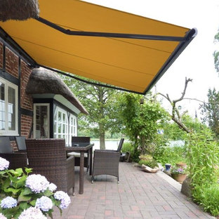 Idee per un patio o portico contemporaneo di medie dimensioni e dietro casa con pavimentazioni in mattoni e un parasole