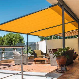 Ispirazione per un patio o portico design di medie dimensioni e dietro casa con piastrelle e un parasole