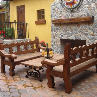 Immagine di un patio o portico boho chic in cortile con un focolare, piastrelle e nessuna copertura