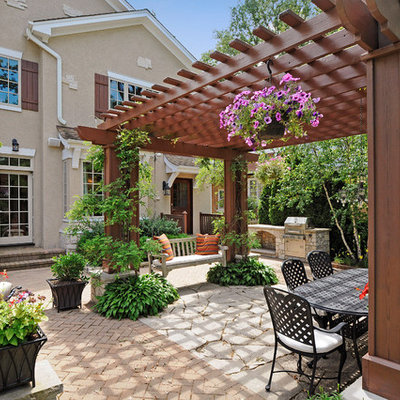 Large elegant backyard stone patio photo in Chicago with a pergola