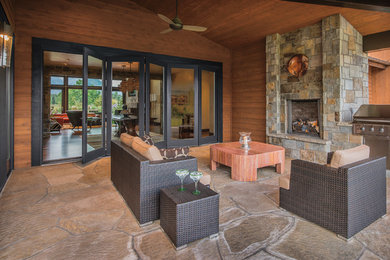 Inspiration for a contemporary backyard stone patio remodel in Kansas City with a fire pit and a roof extension