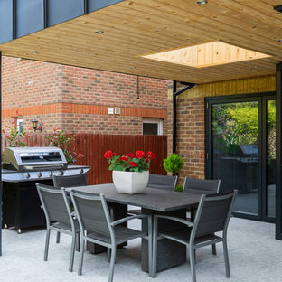 Design ideas for a contemporary back patio in Hertfordshire with an outdoor kitchen, concrete slabs and a roof extension.