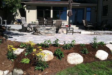 Example of a large classic backyard stone patio design in Other with a fire pit and no cover