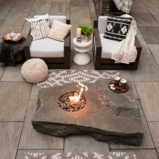 Immagine di un patio o portico moderno di medie dimensioni e dietro casa con un focolare e pavimentazioni in pietra naturale