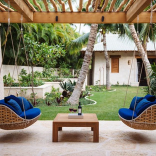 Ispirazione per un patio o portico tropicale di medie dimensioni e dietro casa con pavimentazioni in pietra naturale, una pergola e un giardino in vaso