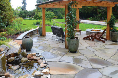 Patio - large traditional backyard stone patio idea in Seattle with a fire pit and a pergola