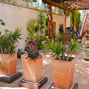 Ejemplo de patio mediterráneo con suelo de baldosas y pérgola
