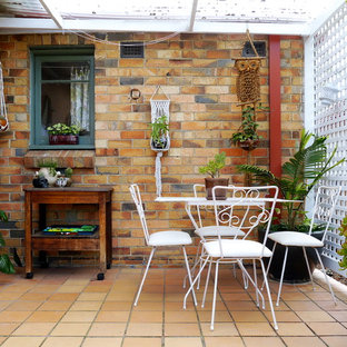 Foto di un patio o portico eclettico di medie dimensioni con un giardino in vaso, piastrelle e una pergola