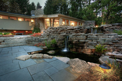 Aménagement d'une grande terrasse arrière contemporaine avec un point d'eau, des pavés en pierre naturelle et aucune couverture.