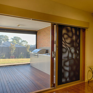 Foto di un grande patio o portico minimalista dietro casa con pedane e un tetto a sbalzo