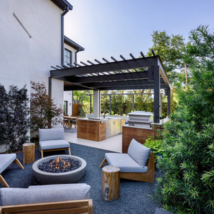 Foto på en mellanstor funkis uteplats på baksidan av huset, med en öppen spis och en pergola