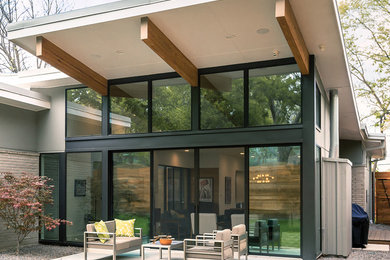 Idées déco pour une terrasse arrière contemporaine de taille moyenne avec une dalle de béton et une extension de toiture.