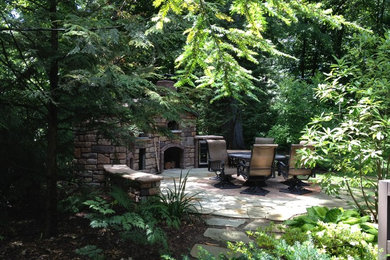 Ejemplo de patio clásico de tamaño medio en patio trasero con chimenea y adoquines de piedra natural