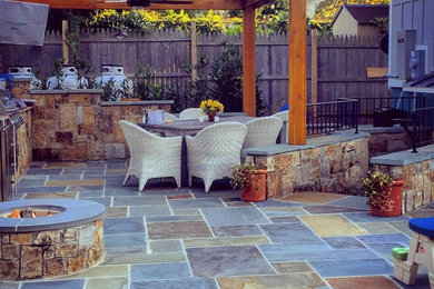 Ejemplo de patio tradicional renovado de tamaño medio en patio trasero con brasero, adoquines de piedra natural y pérgola