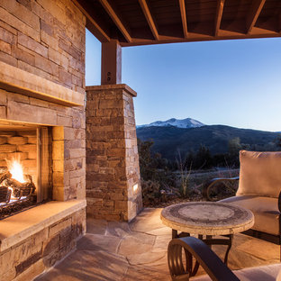 Idee per un patio o portico rustico di medie dimensioni e dietro casa con un focolare, pavimentazioni in pietra naturale e un tetto a sbalzo