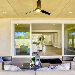 Idee per un grande patio o portico chic dietro casa con un caminetto, cemento stampato e un tetto a sbalzo
