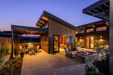 Example of a mid-sized mountain style courtyard concrete paver patio fountain design in Portland with a roof extension