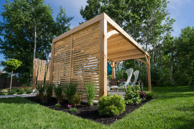 Diseño de patio actual de tamaño medio en patio trasero con losas de hormigón y pérgola