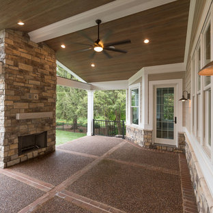 Immagine di un grande patio o portico american style dietro casa con un focolare, un tetto a sbalzo e lastre di cemento