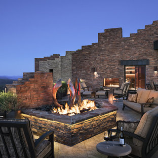 Idee per un ampio patio o portico stile americano dietro casa con un focolare, piastrelle e nessuna copertura