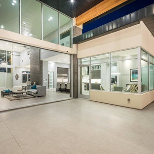 Idee per un ampio patio o portico moderno dietro casa con pavimentazioni in pietra naturale e un parasole