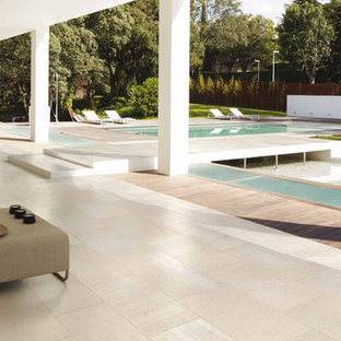 Foto di un ampio patio o portico moderno dietro casa con piastrelle e un tetto a sbalzo