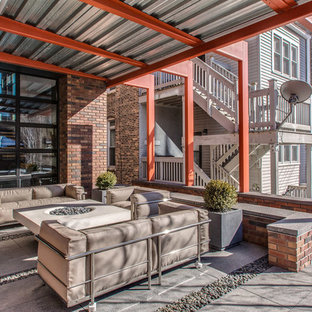 Ispirazione per un ampio patio o portico industriale dietro casa con un focolare, lastre di cemento e un parasole