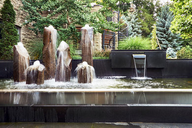 Patio fountain - modern backyard stone patio fountain idea in Toronto with a pergola