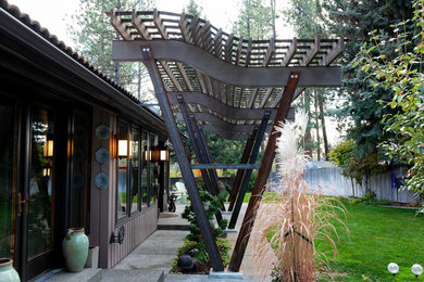 Diseño de patio moderno en patio trasero con losas de hormigón y pérgola
