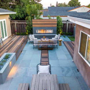 Immagine di un grande patio o portico contemporaneo dietro casa con un caminetto, pedane e nessuna copertura